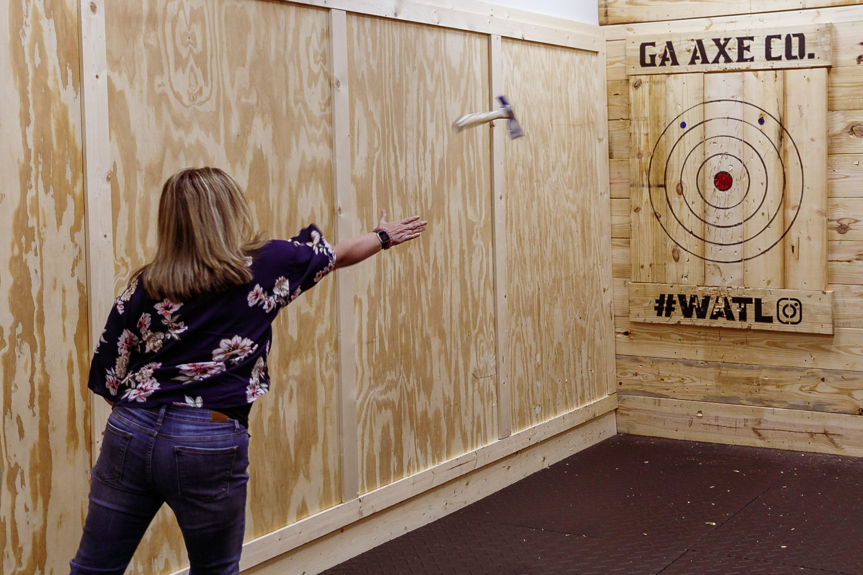 woman throwing axe at indoor target